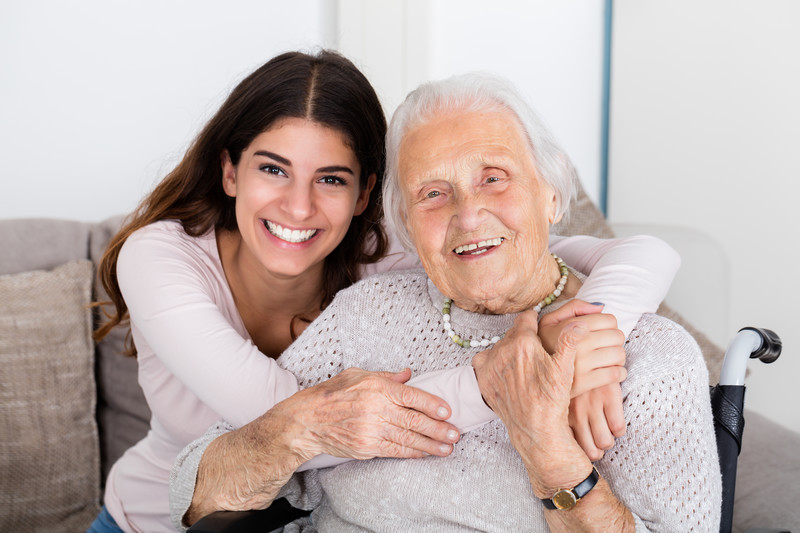 caregiver hugging senior woman and smiling
